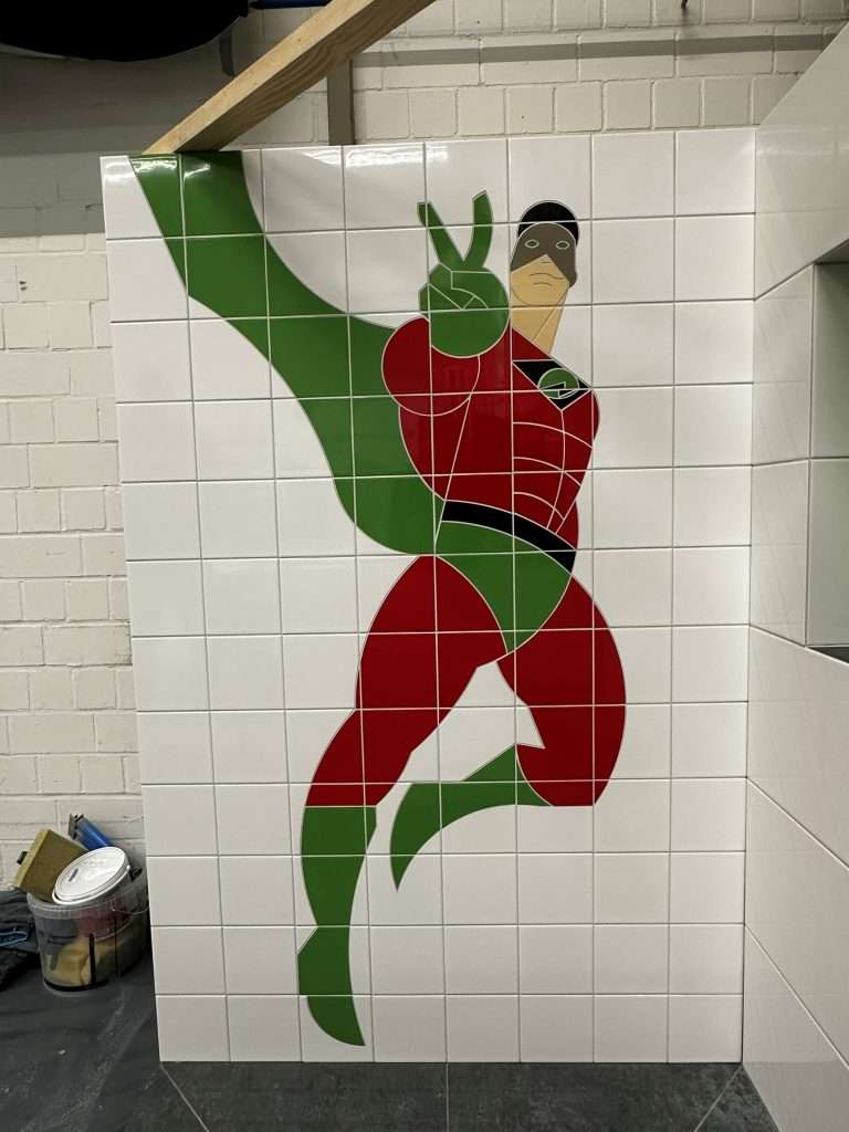 Fliesenwand mit grafischem Superhelden-Motiv im Badezimmer.