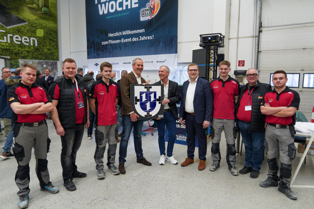 Gruppenfoto bei Fliesen-Event mit Teilnehmern und Auszeichnung.