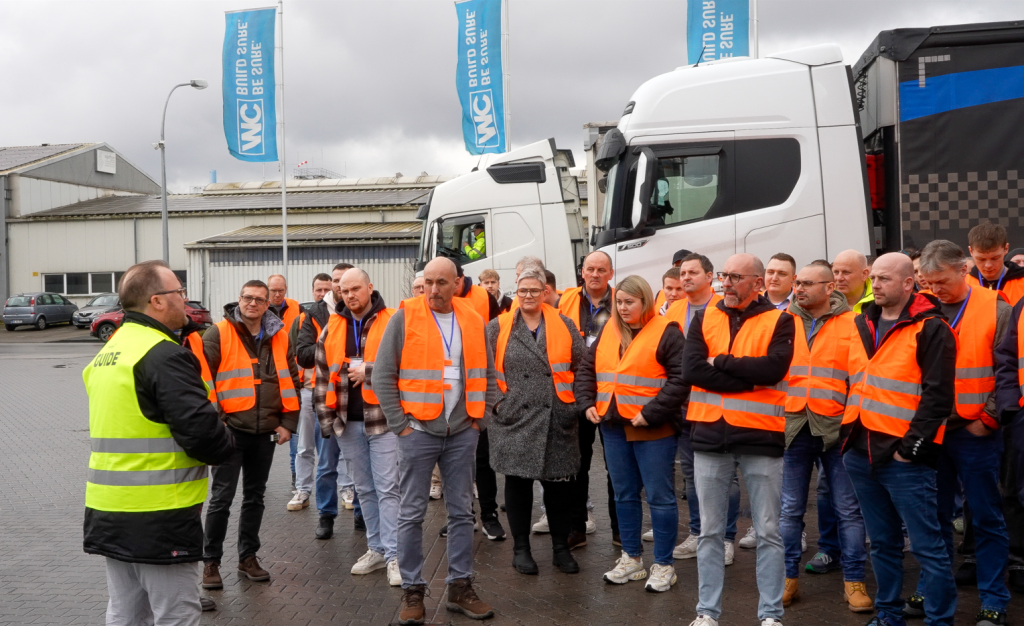 Gruppe bei Werksführung im Außenbereich mit Sicherheitswesten.